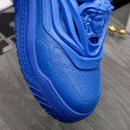 Blue leather-look sneakers close-up of molded lion-head detail and stitching