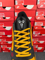 Yellow and black sneaker back view with fin-like emblem and yellow laces
