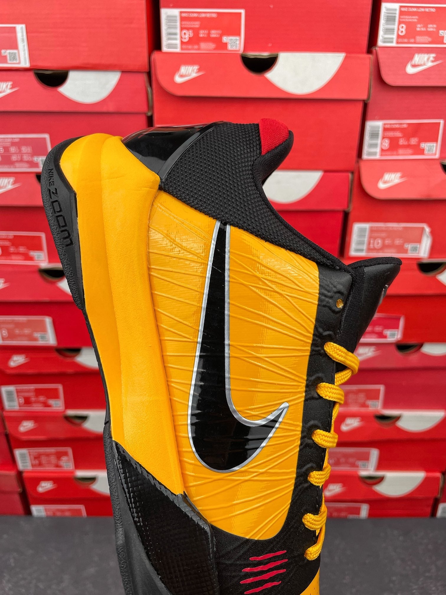Yellow and black sneaker angled view with black mesh collar and yellow laces