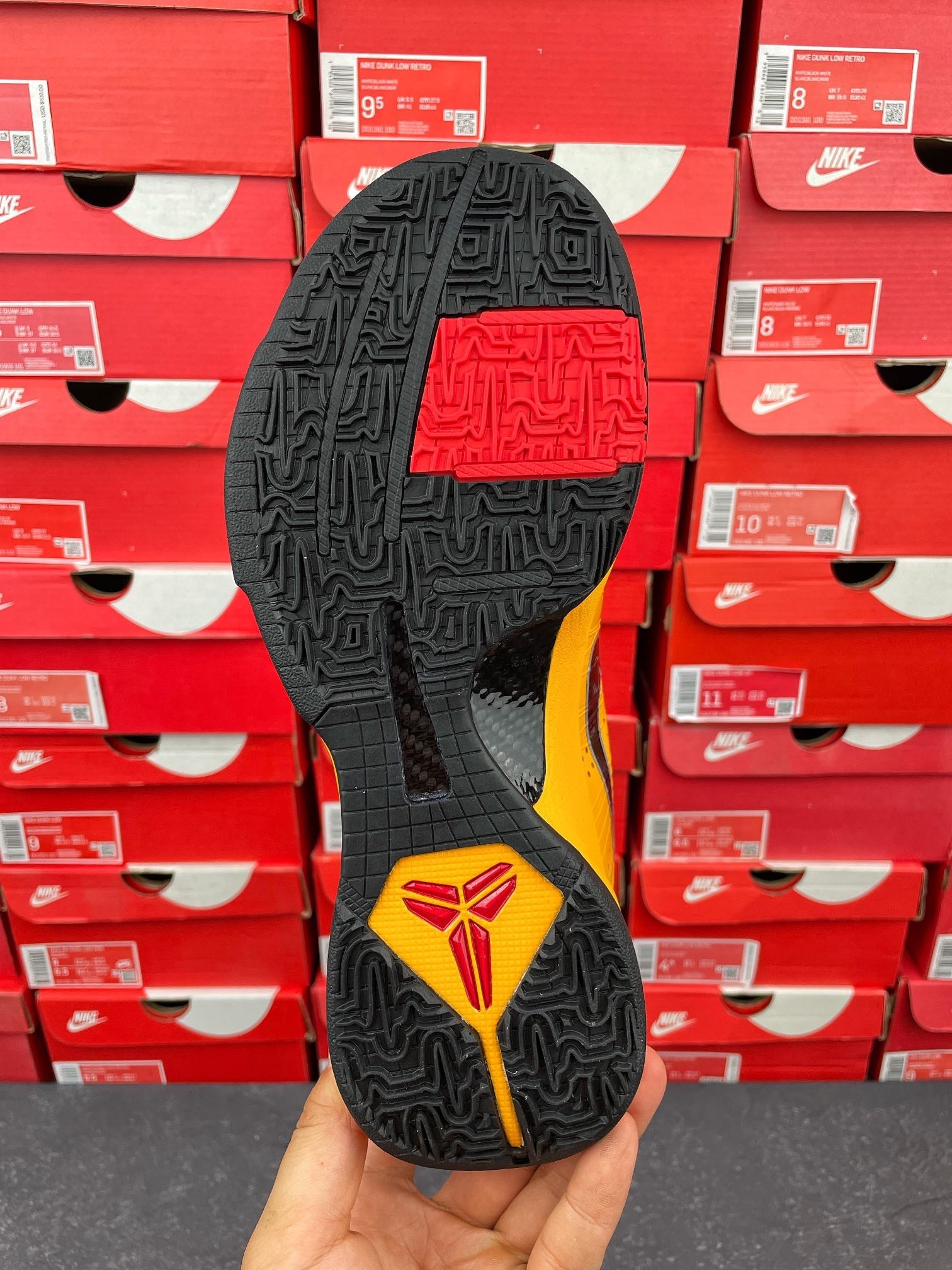 Black outsole with textured tread and yellow-red emblem patch