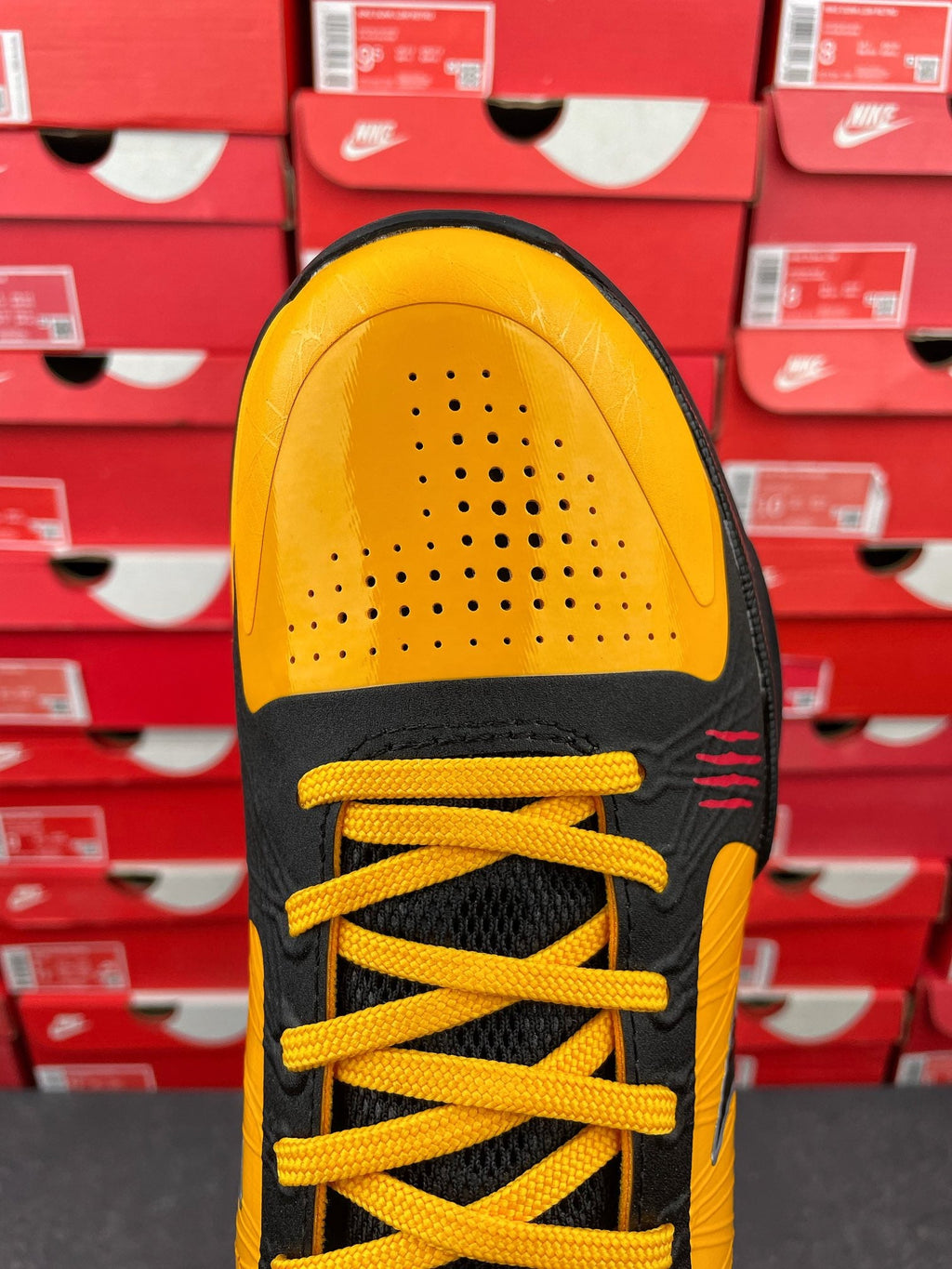 Yellow and black sneaker with lace-up visible and perforated toe area