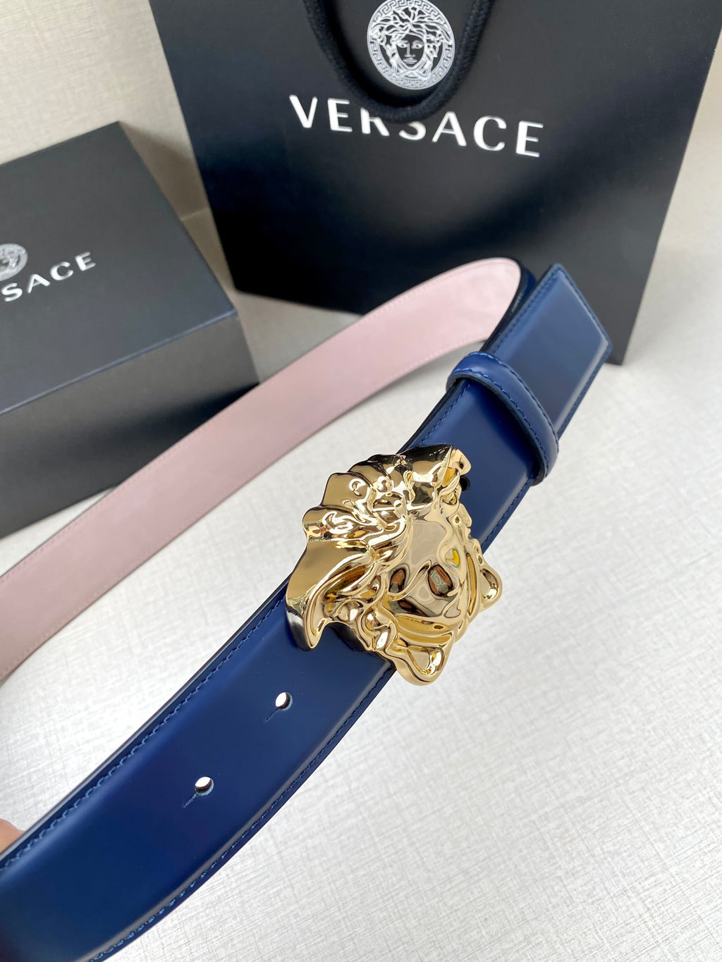 Blue leather belt with ornate gold Medusa buckle and stitched edge