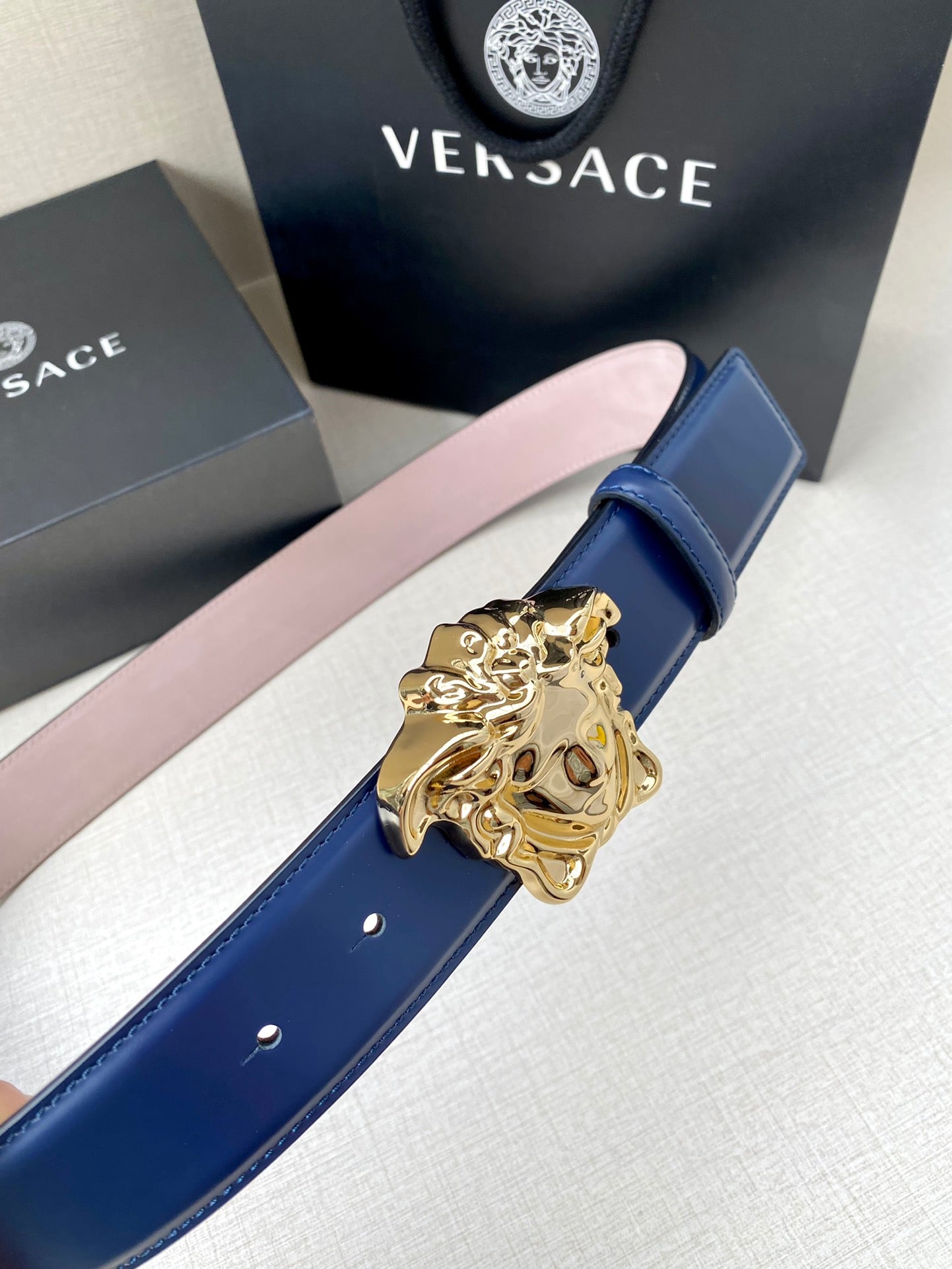 Blue leather belt with ornate gold Medusa buckle and stitched edge