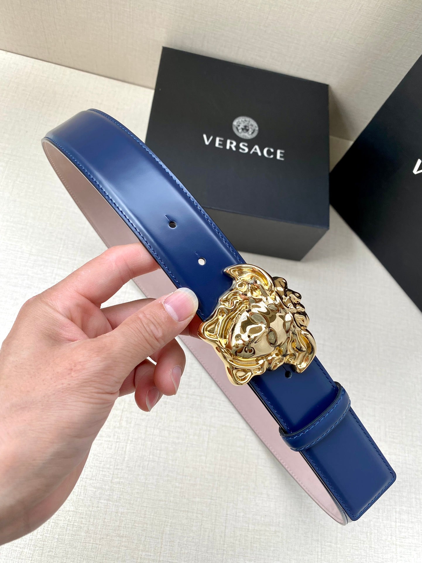 Blue leather belt with gold Medusa buckle detail and punched holes