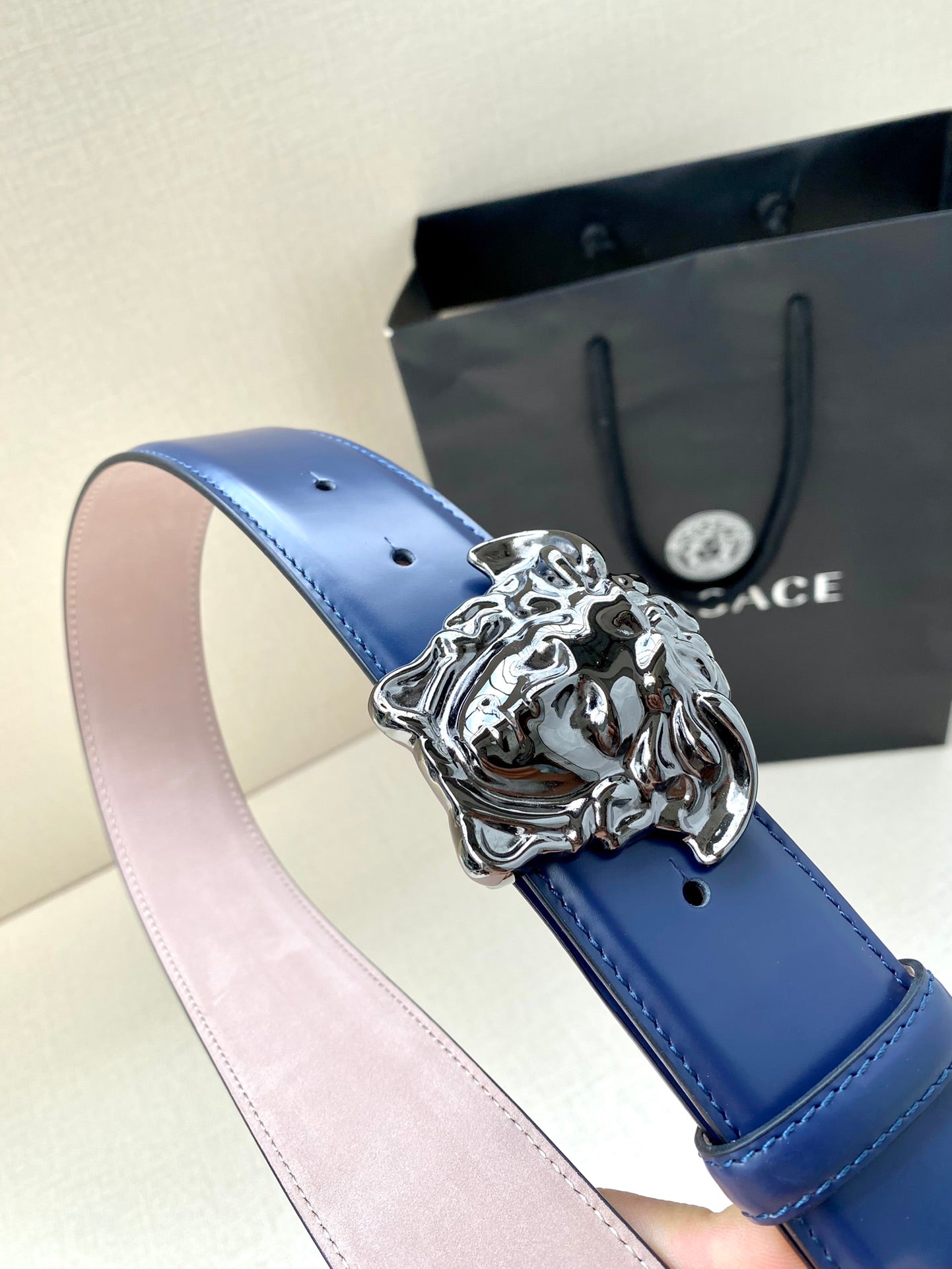 Blue leather belt with silver lion-head buckle and light pink underside
