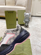 Gucci unisex sneakers close-up, GG canvas upper with pink trim and thick navy sole.
