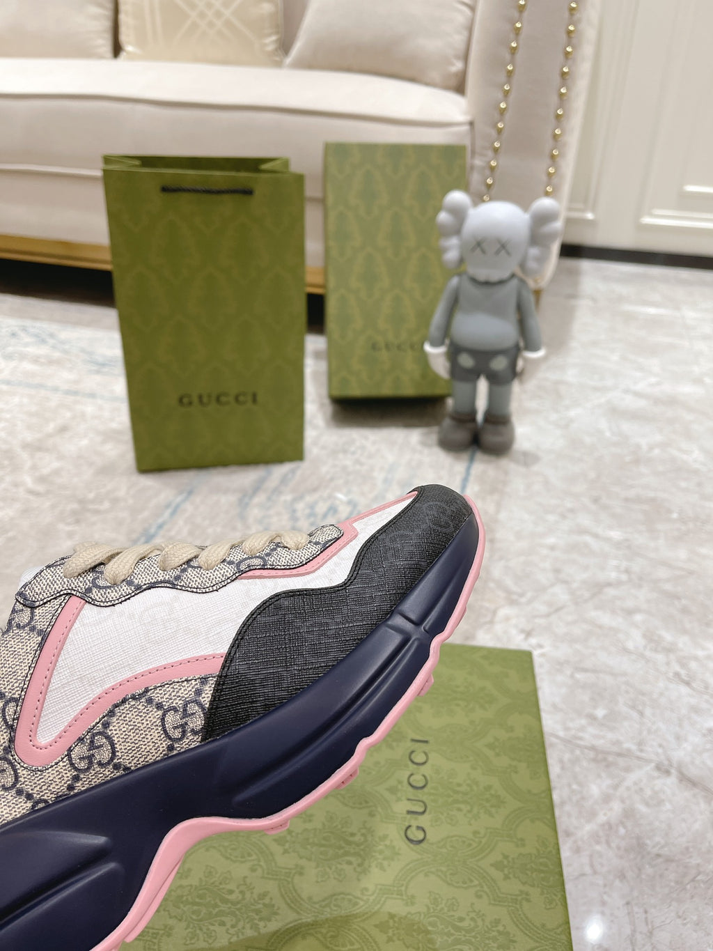 Gucci unisex sneakers close-up, GG print quarter with pink outline and navy sole edge.
