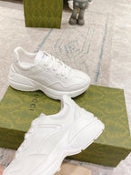 White lace-up sneakers side-by-side on green boxes, chunky sole and side stripe
