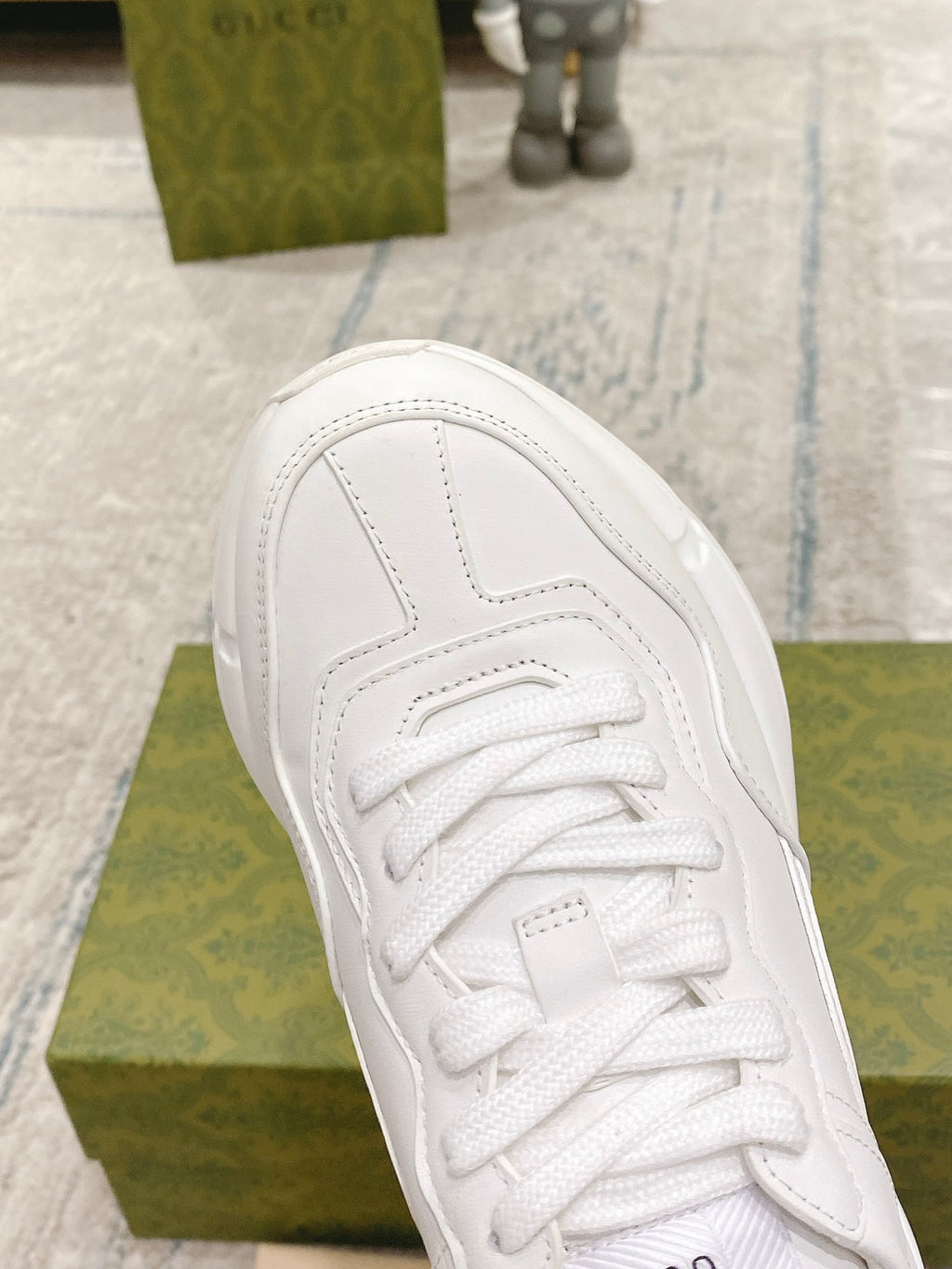 Close-up of white lace-up sneaker upper with stitched panel lines and logo on tongue