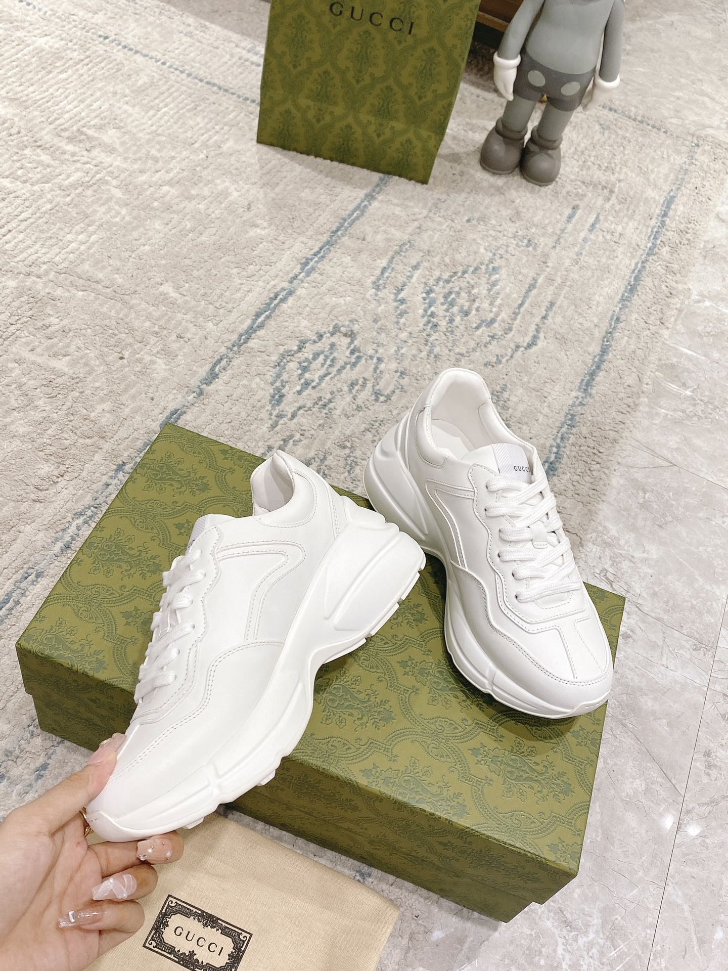 White lace-up sneakers displayed on green boxes, side panels and stitching visible