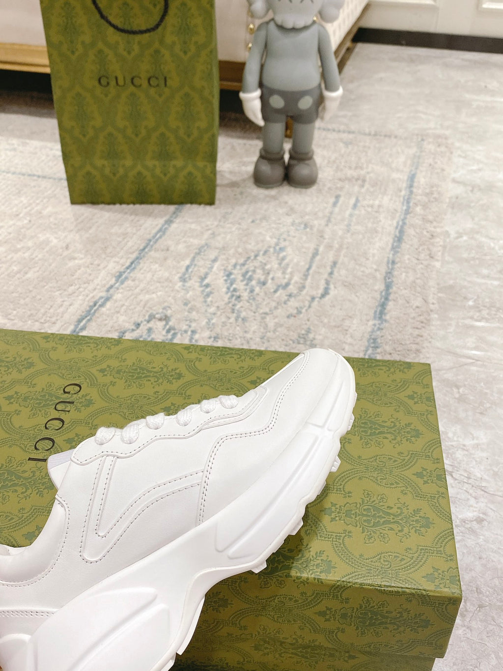 White sneaker angled on green box, lace-up upper and sculpted sole profile