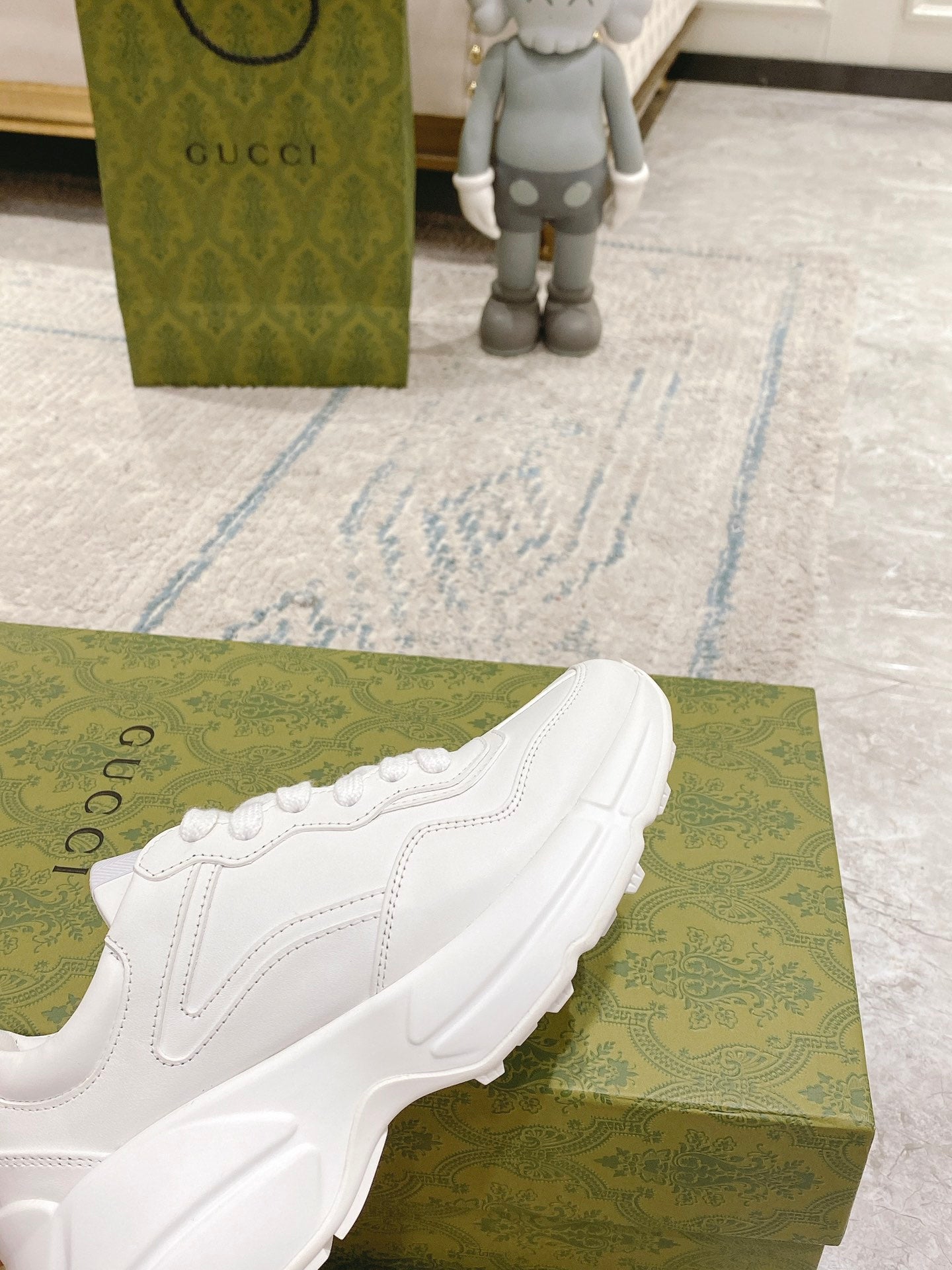 White sneaker angled on green box, lace-up upper and sculpted sole profile