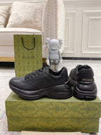 Pair of dark/black Gucci lace-up sneakers, front and heel view with logo on back