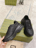 Close view of dark/black Gucci lace-up sneakers, two shoes on green box
