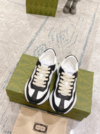 Pair of black and white unisex sneakers with cream laces, side view