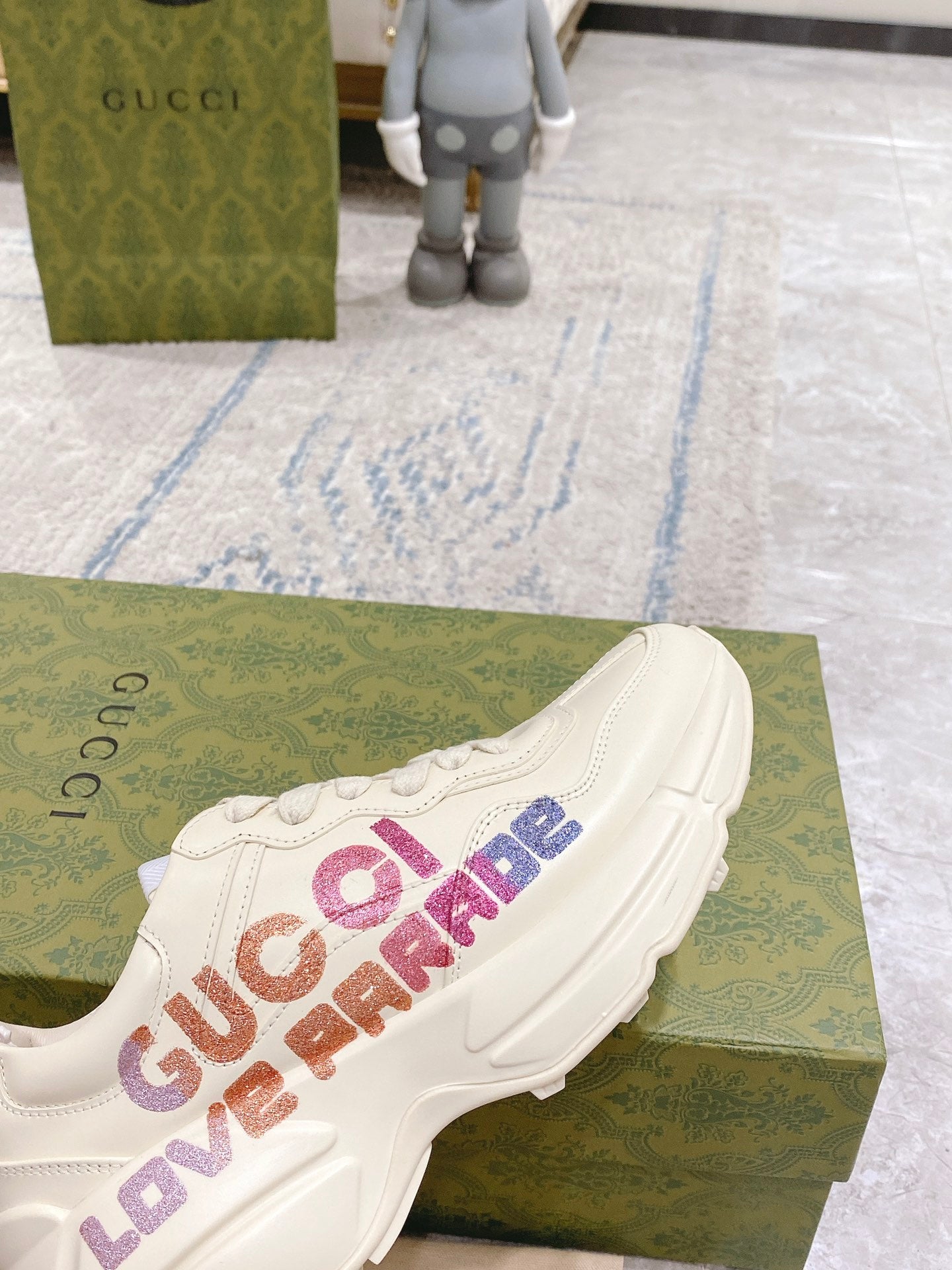 Close view of white Gucci unisex sneakers with multicolor LOVE PARADE logo on side