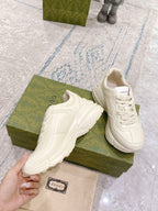White lace-up sneakers on green box, smooth leather upper