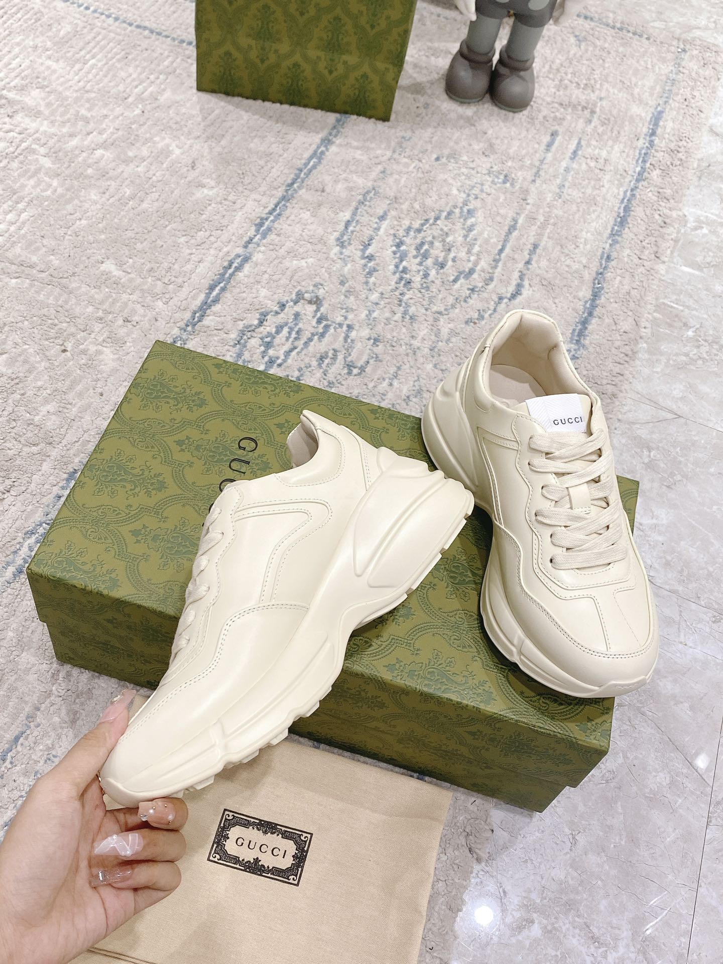 White lace-up sneakers on green box, smooth leather upper