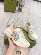 White lace-up sneakers held in hand, with The North Face Gucci multicolor logo