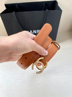 Orange leather belt with silver double-C buckle, close-up of belt strap and holes
