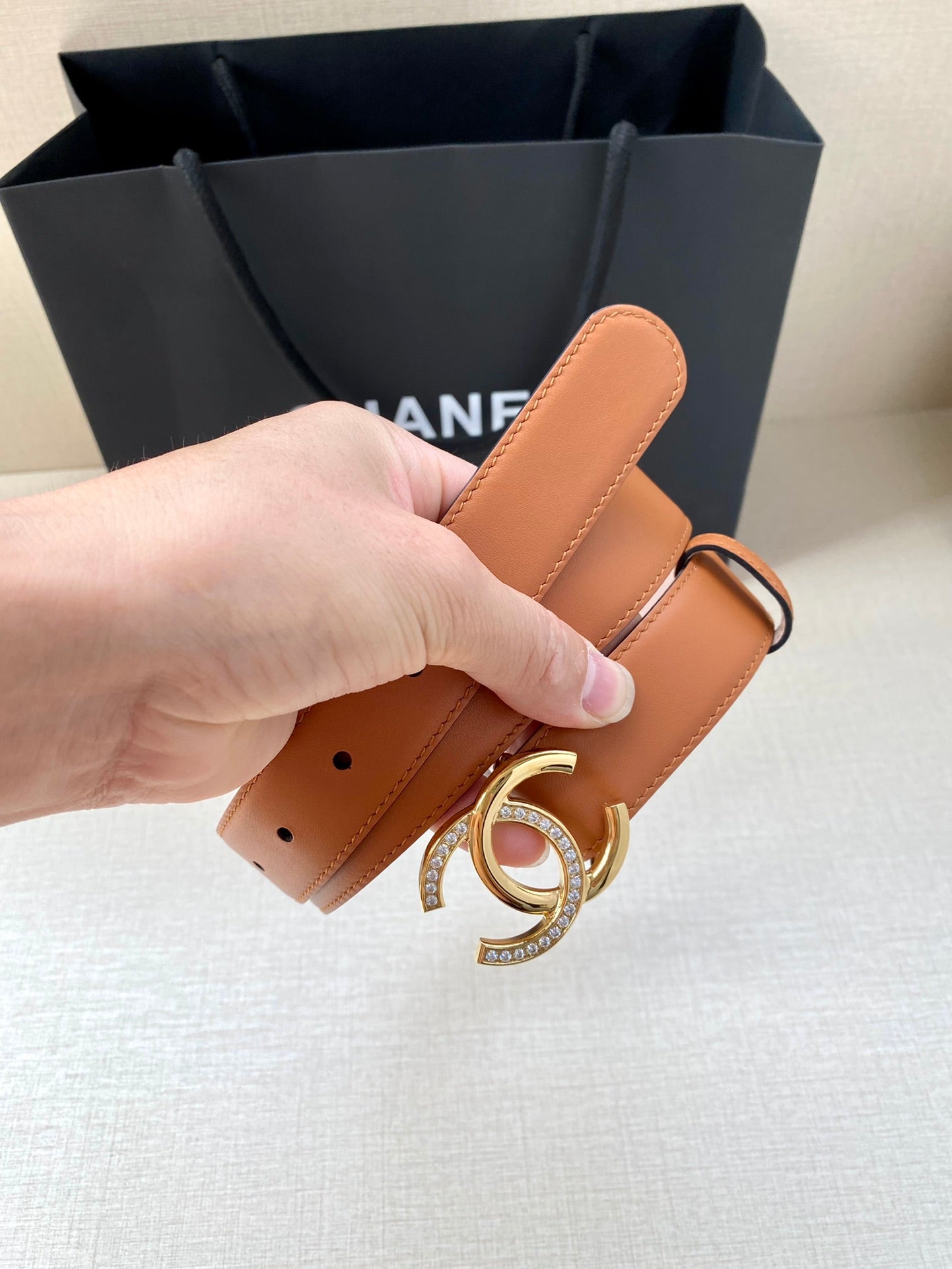 Orange leather belt with silver double-C buckle, close-up of belt strap and holes