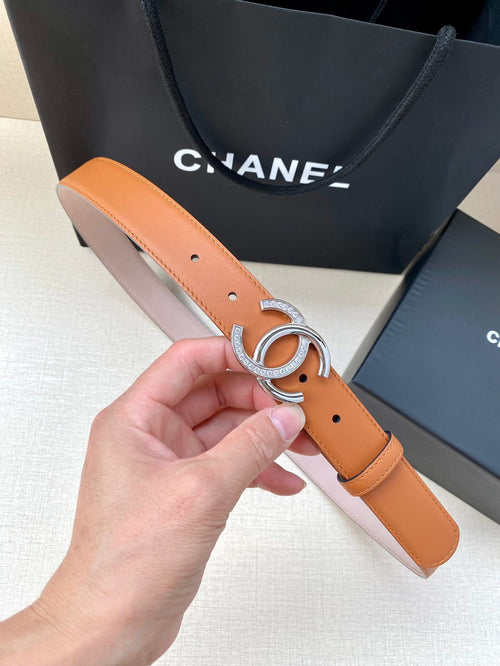 Orange leather belt with silver double-C buckle and punched holes, held in hand
