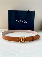 Orange leather belt with gold double-C buckle and punched holes, laid on surface