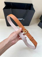 Orange leather belt with silver double-C buckle, two-handled view in front of bags