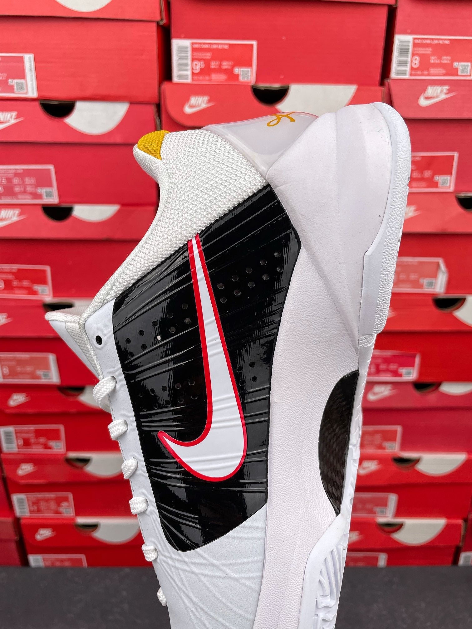 White and black high-top sneakers with red swoosh stripe and yellow collar