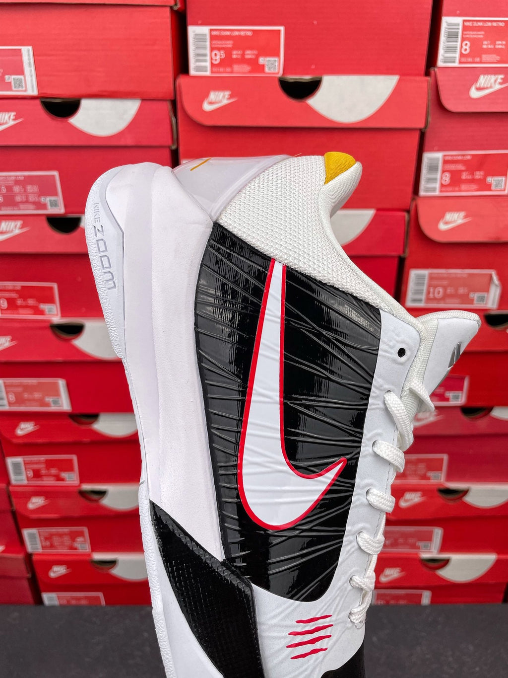 White and black high-top sneakers with red swoosh stripe detail on side