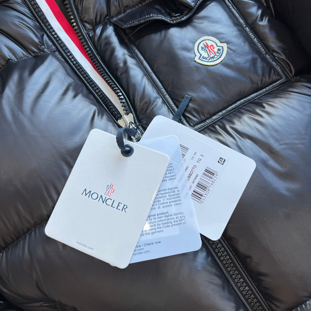 Long puffer jacket with hanging Moncler tags on front zipper area