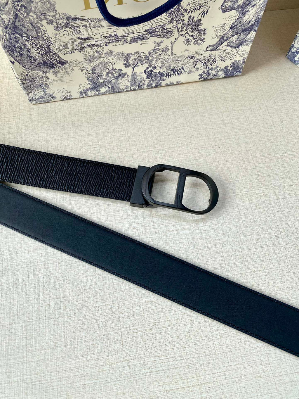 Dior belt side view with dark blue strap and black D-ring style buckle