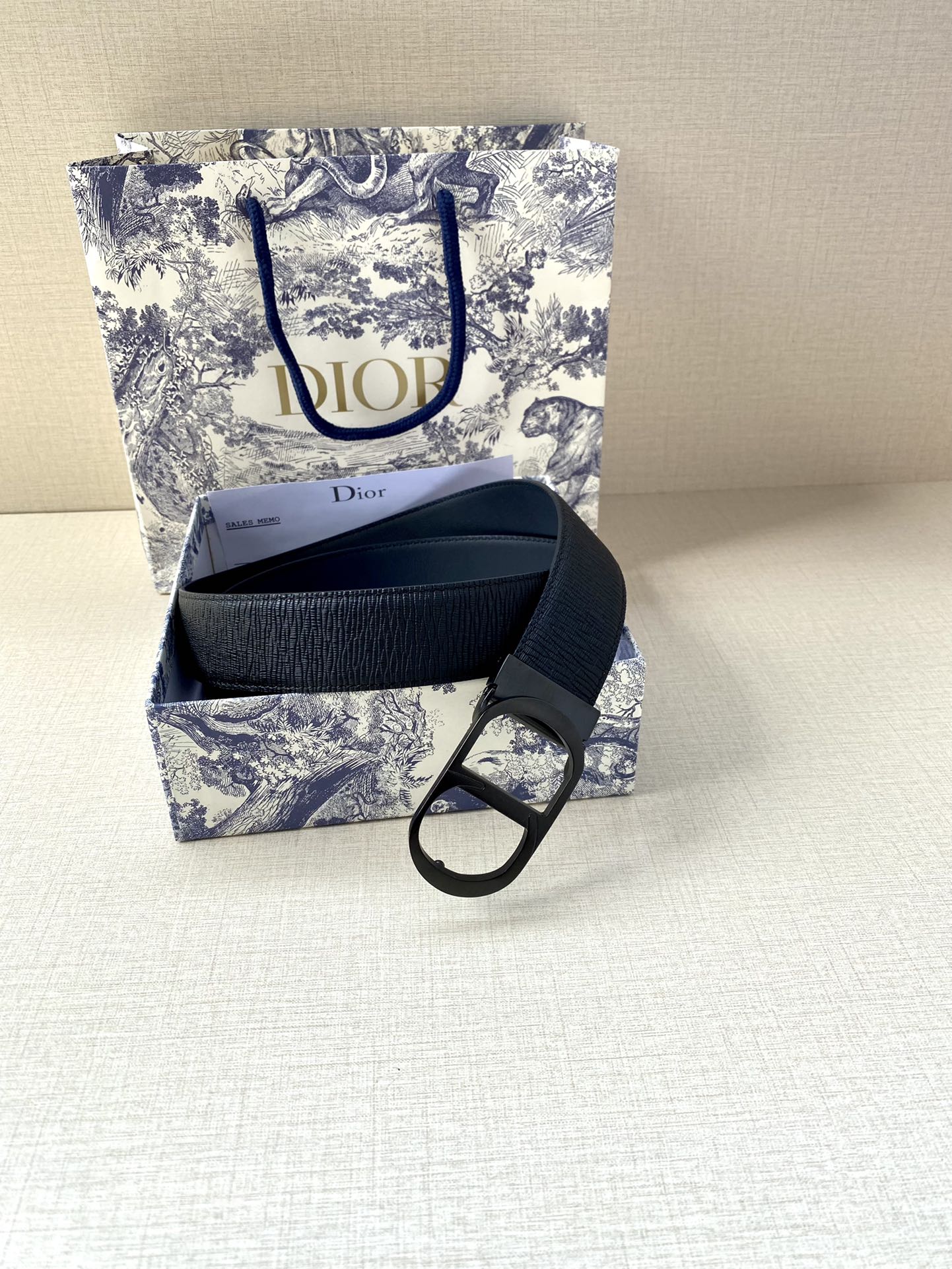 Dior belt laid out with dark blue strap and black buckle over textured leather