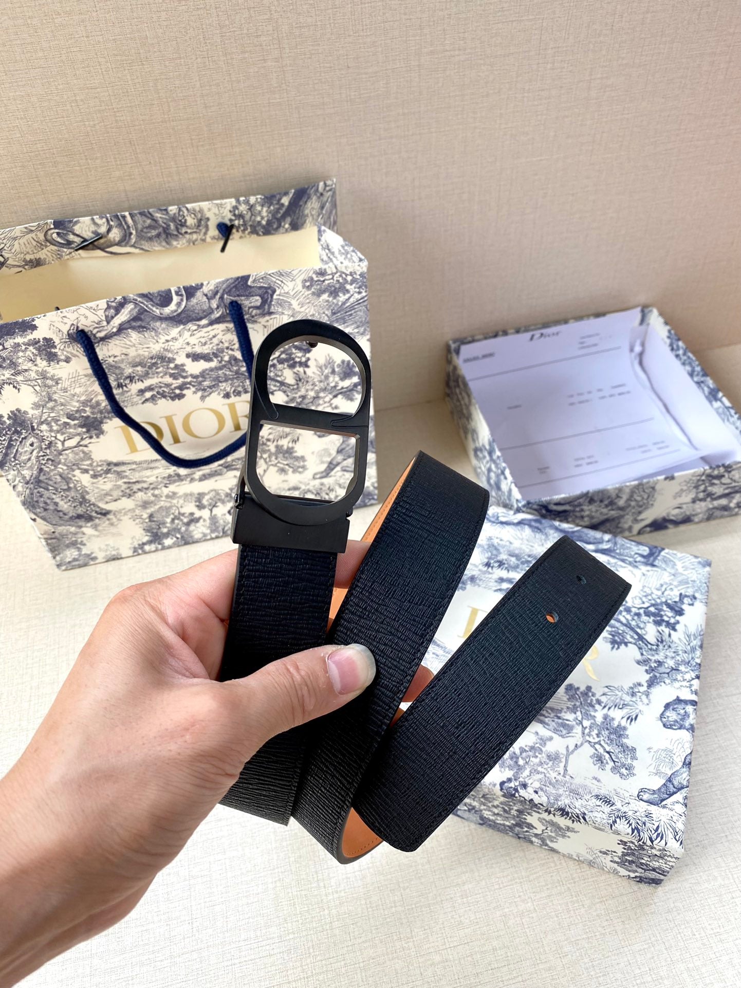 Dior belt with dark navy textured strap and silver oval buckle, held up