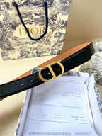 Dior belt with black strap, tan lining, and gold-tone buckle on display