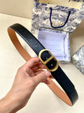 Dior belt with black leather-look strap and gold-tone oval buckle, held in hand
