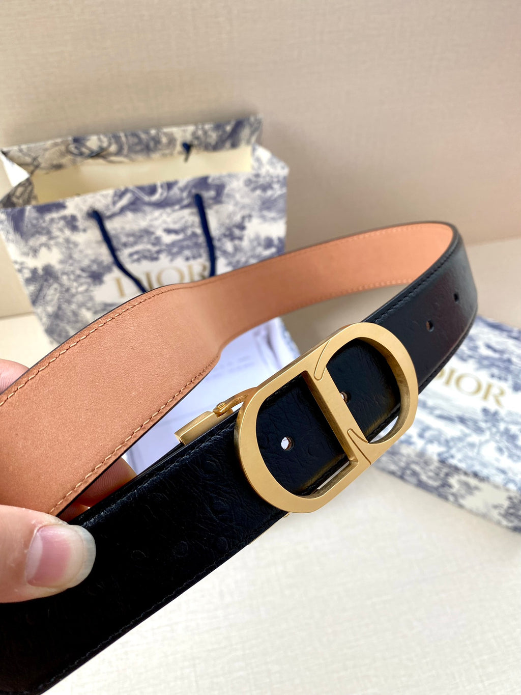 Dior belt close-up: black strap with tan lining and gold-tone buckle