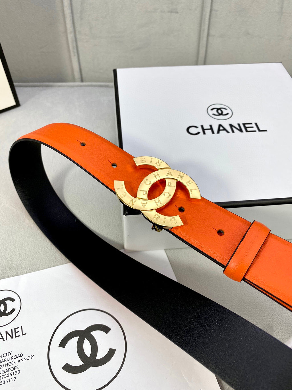 Orange leather belt with gold CC buckle and black underside strap