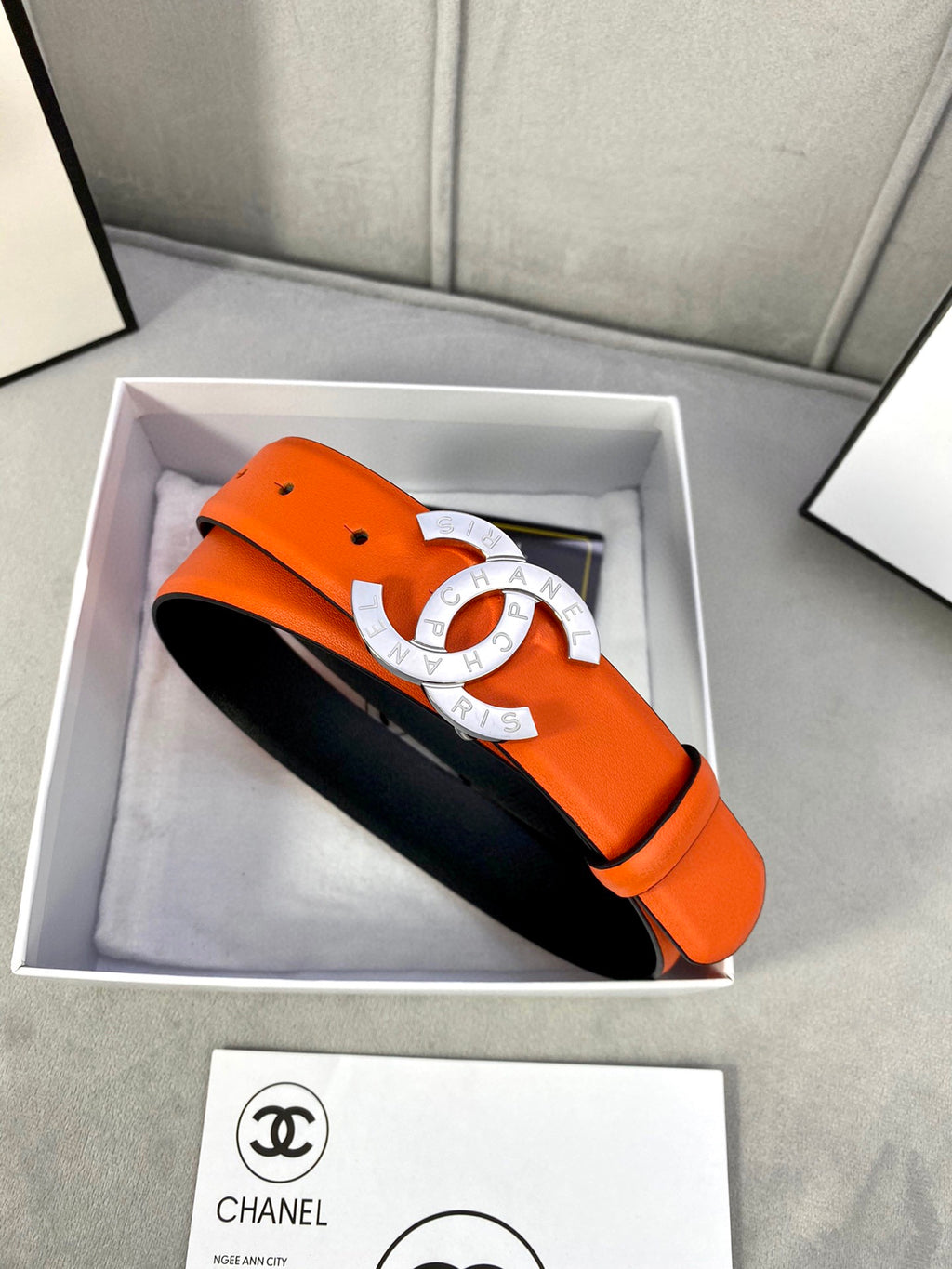 Orange leather belt with gold CC buckle, black underside visible