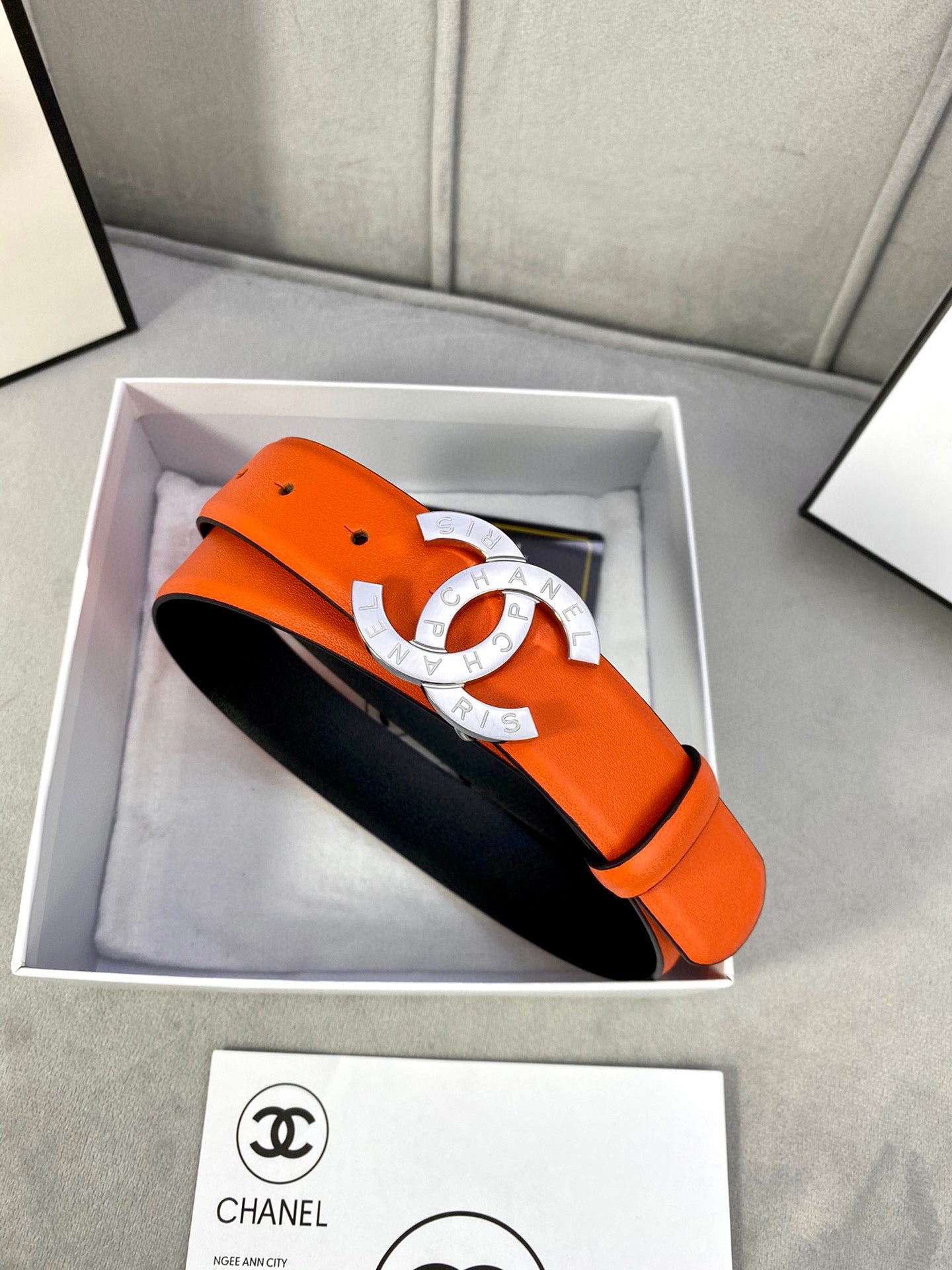 Orange leather belt with gold CC buckle, black underside visible