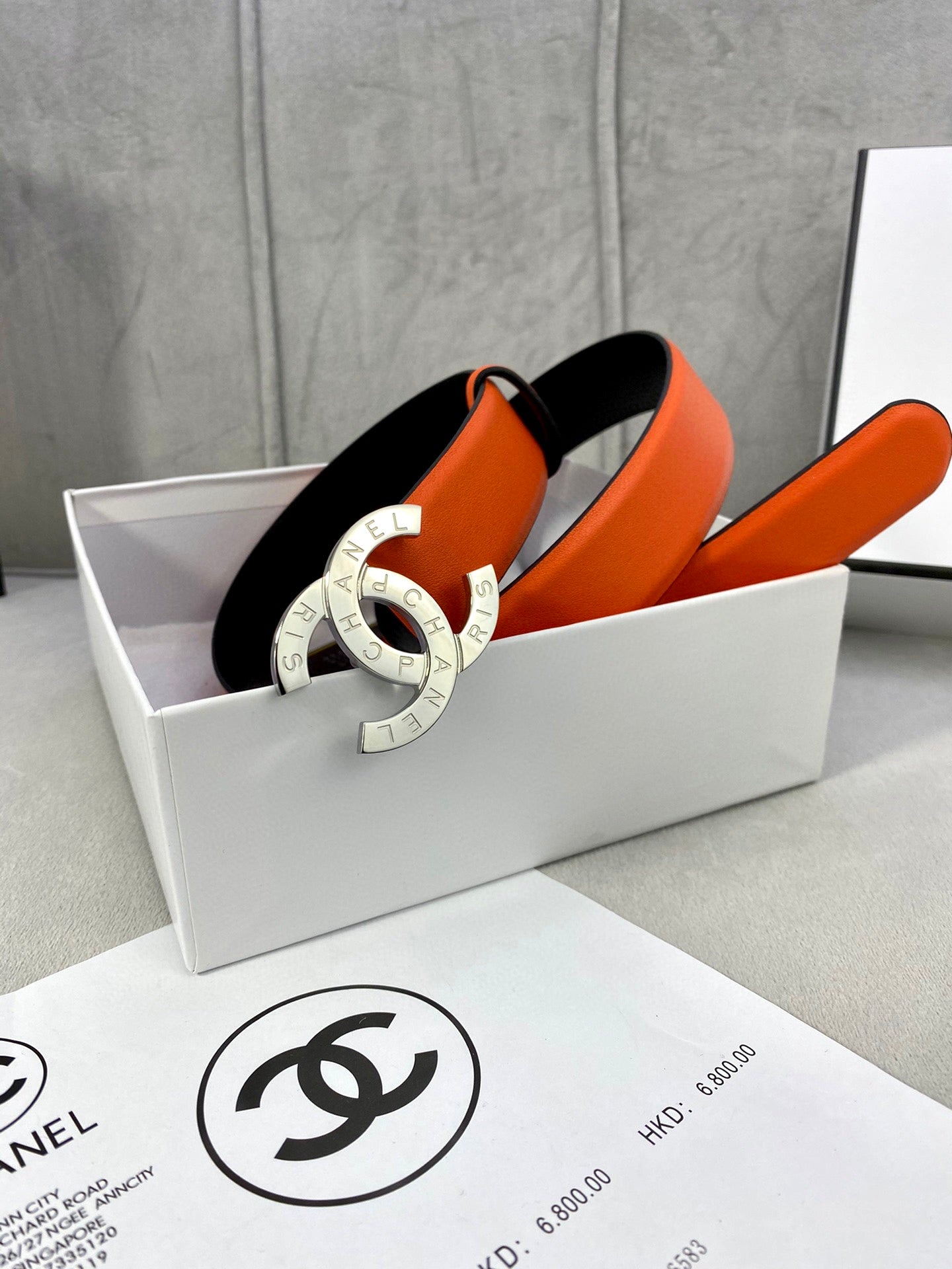 Orange leather belt with gold CC buckle, shown in a gift box