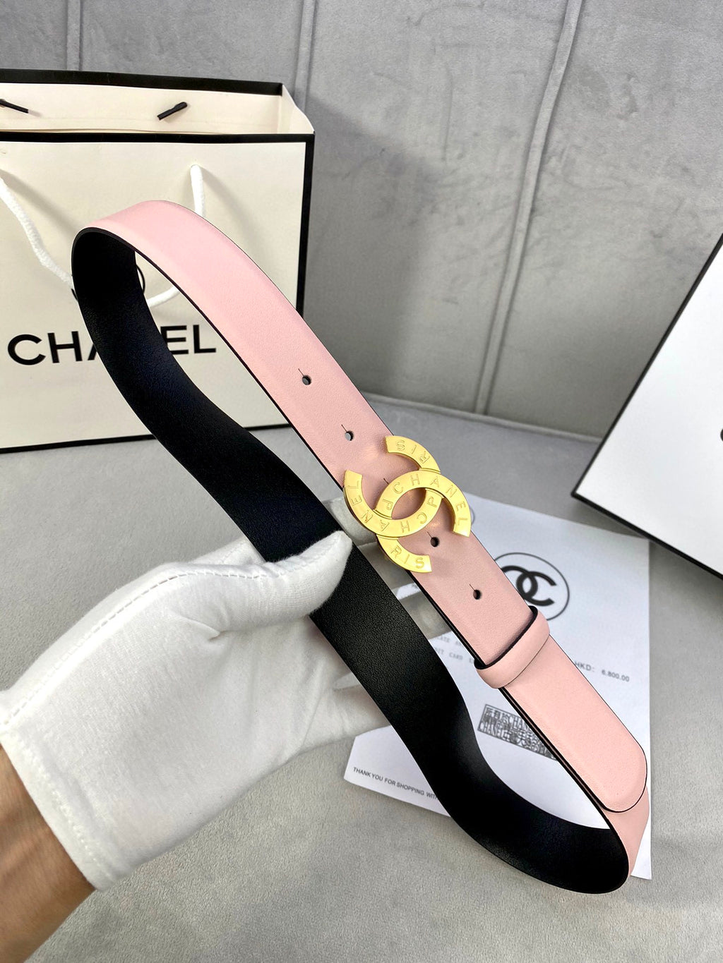 Pink leather belt with gold-tone double-ring logo buckle, shown with inner black lining.
