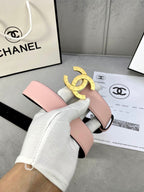 Pink leather belt with gold-tone double-ring logo buckle in front of product box.