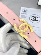 Pink leather belt close-up of gold-tone double-ring Chanel logo buckle over holes.