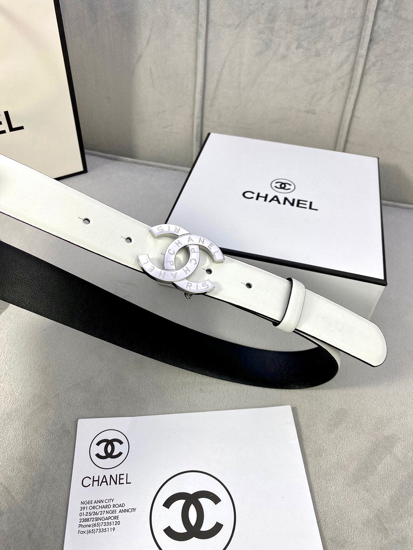 Chanel belt in pale white leather with silver-toned CC buckle, shown on box