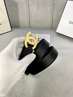 Black leather belt with gold CC buckle, held in white glove