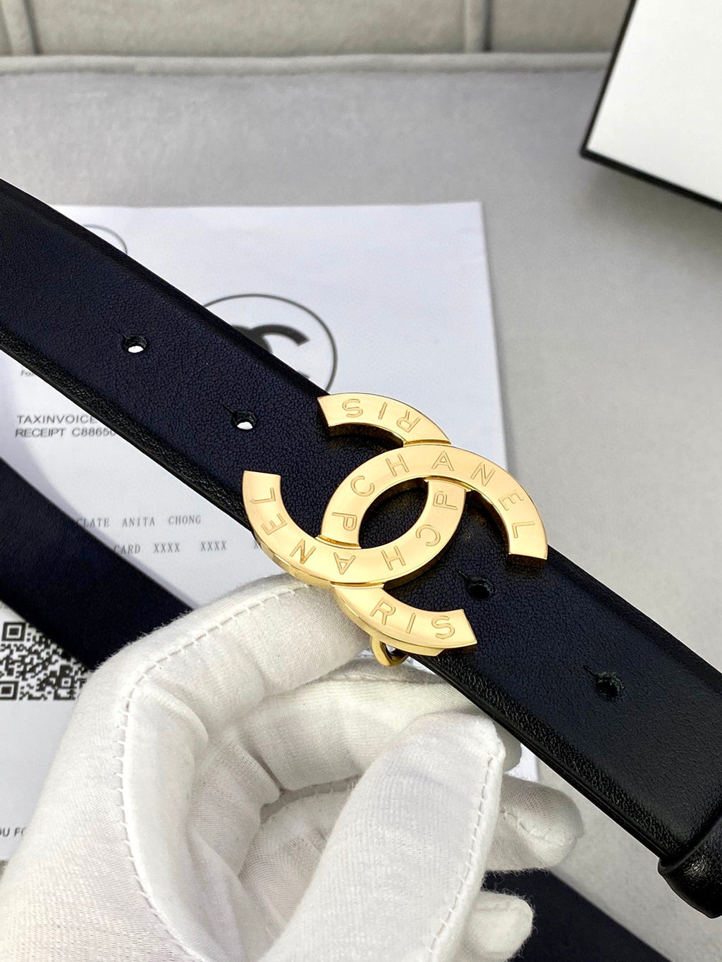 Dark navy leather belt close-up with gold CC buckle and strap holes