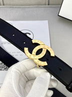 Dark navy leather belt close-up with gold CC buckle and strap holes