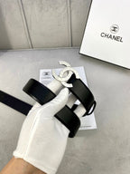 Black leather belt with silver CC buckle, shown on surface