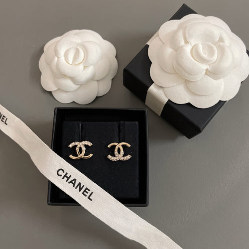 Gold-tone CC stud earrings with rhinestones, displayed in black box